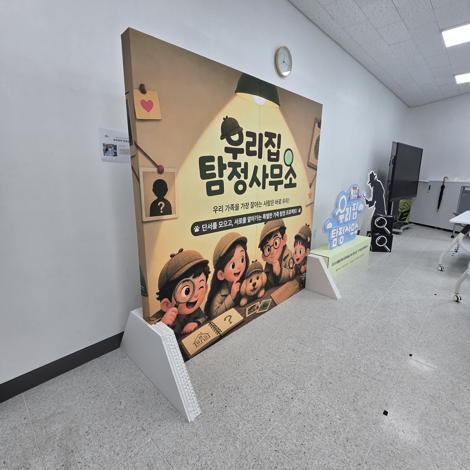측면에서 본 동화책형 포토존. 허니콤보드로 제작된 입체 구조가 명확히 보임. 베이지색 측면과 흰색 허니콤 격자 구조의 지지대가 드러남. 뒷편에 다른 전시물(검정색 인물 실루엣 스카시)이 함께 보임