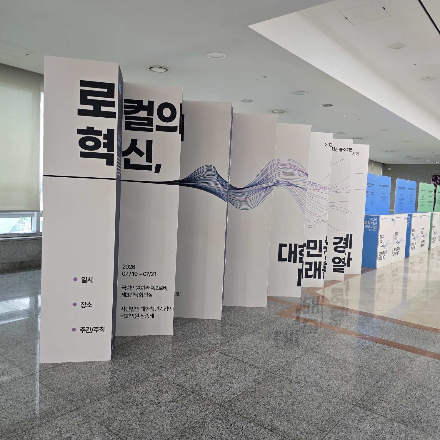 흰색 기본 패널 다수 연결. '토컬의 혁신', '일시·장소·주관/주최' 정보, 물결 라인 그래픽. '대한민국 경제 미래를 열다' 슬로건. 뒤쪽 블루 패널 일부 보임.