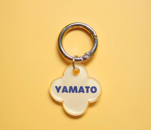 흰색 반투명 아크릴 소재의 네잎클로버 형태 키링. 중앙에 파란색으로 'YAMATO' 문구가 인쇄되어 있으며, 은색 키링 고리와 연결됨