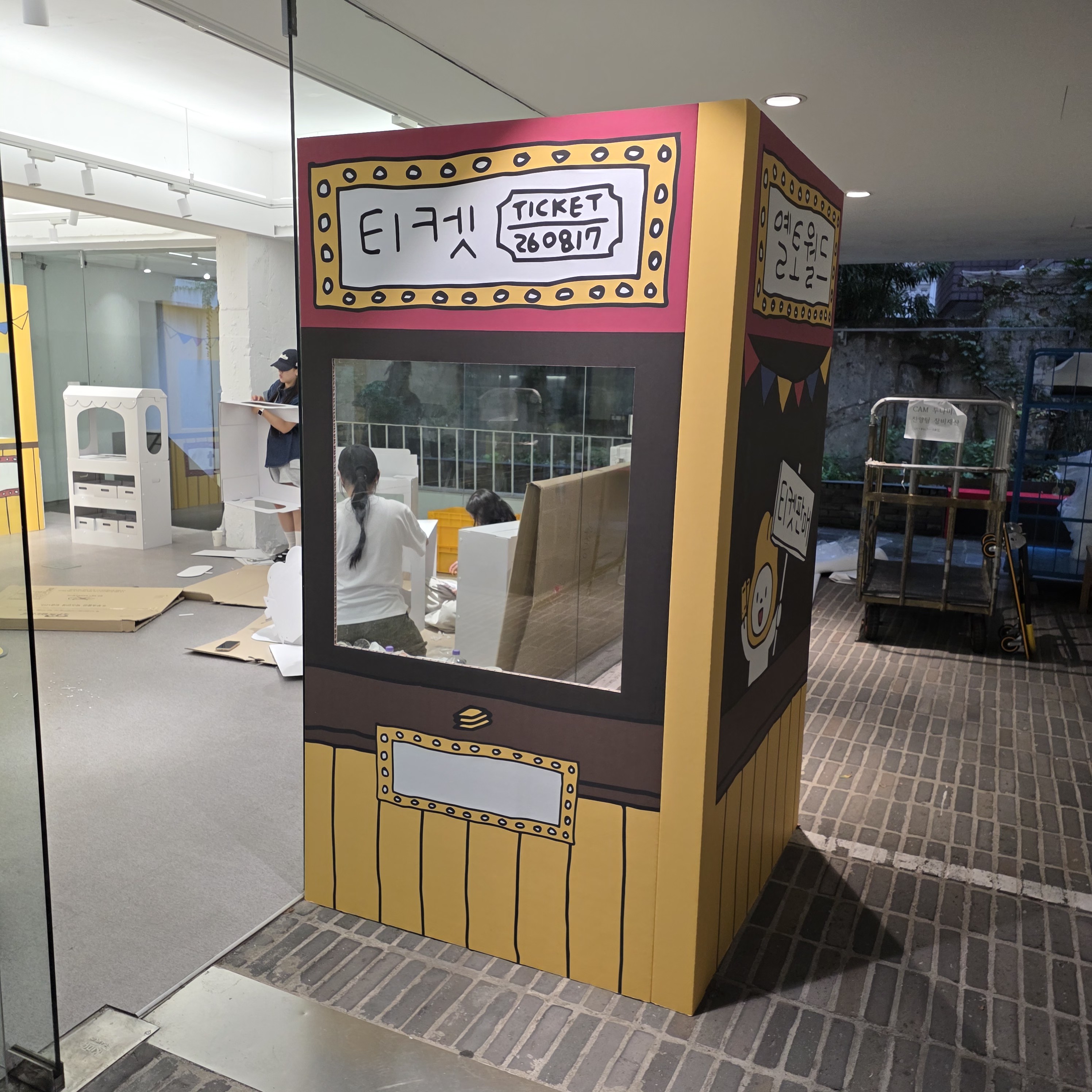 사진 0과 동일한 티켓 모양 포토존의 측면 각도. 옆면에는 '옐로월드' 문구와 일러스트가 추가로 인쇄됨. 두께감 있는 패널 형태로 제작.